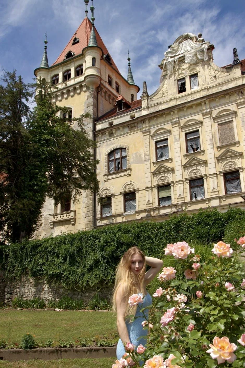 Urška among roses in front of a historic mansion