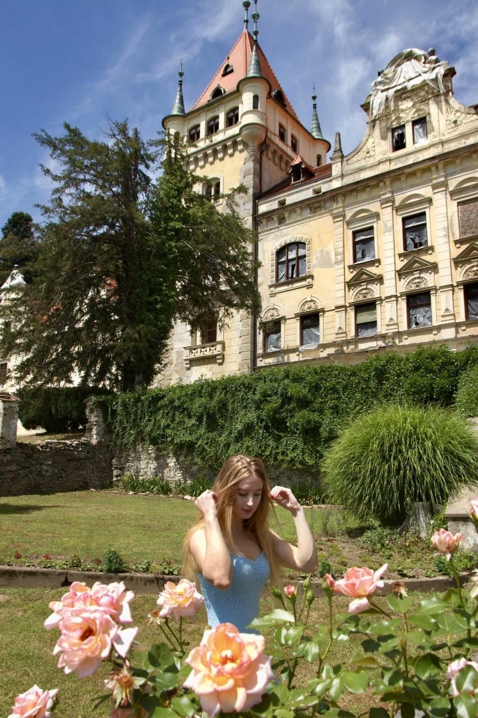 Urška in a rose garden in front of a historic mansion