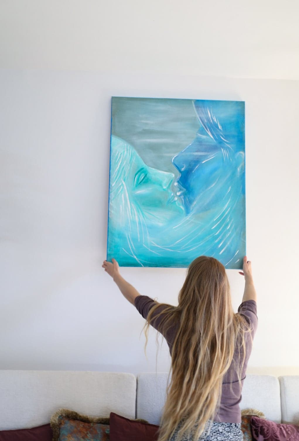 Urška hanging the turquoise canvas above the sofa