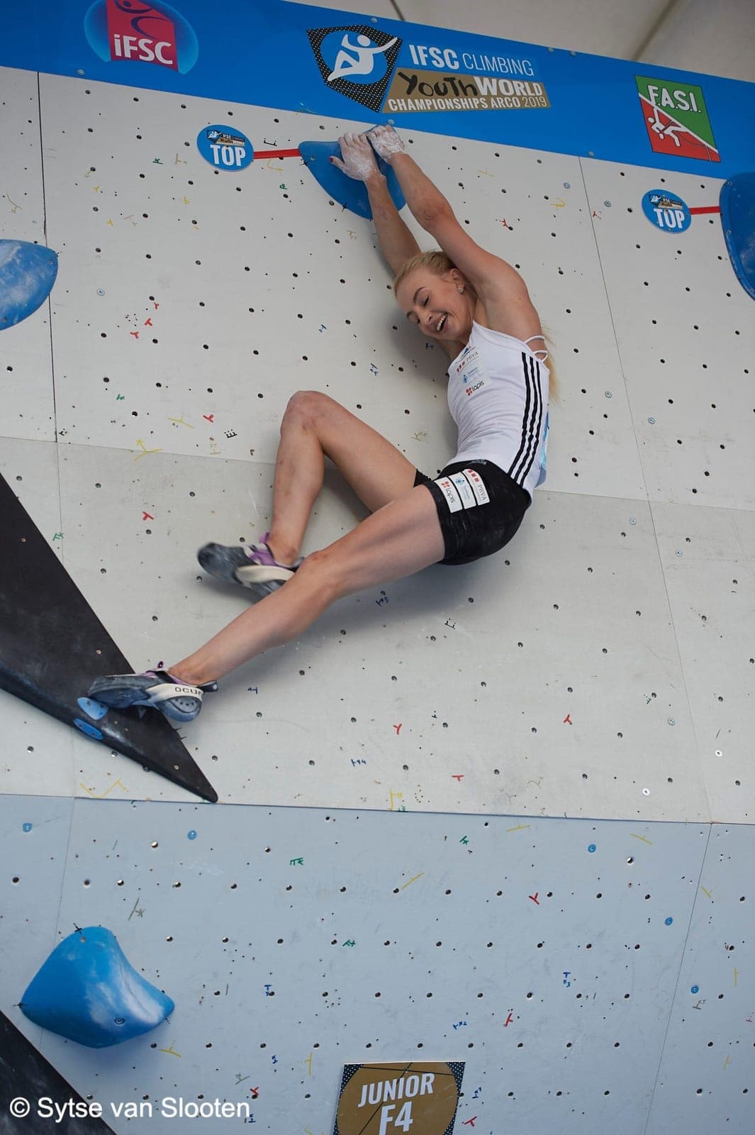 Urška in a World Cup bouldering final, stretched across a blue wall