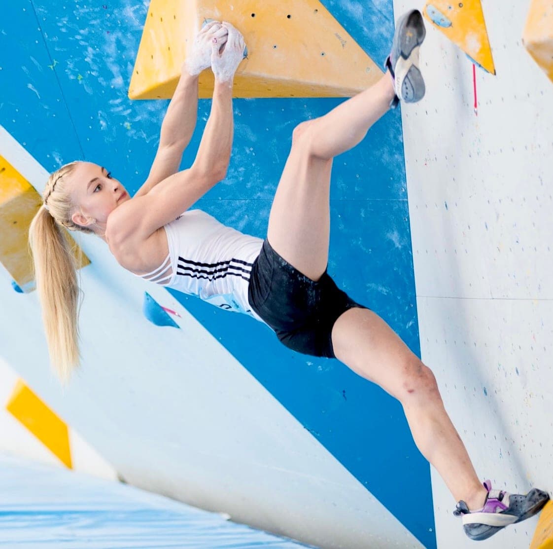 Urška stepping high on a blue and yellow wall