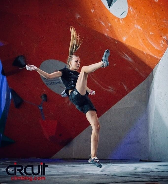 Urška high-stepping on a red and orange wall