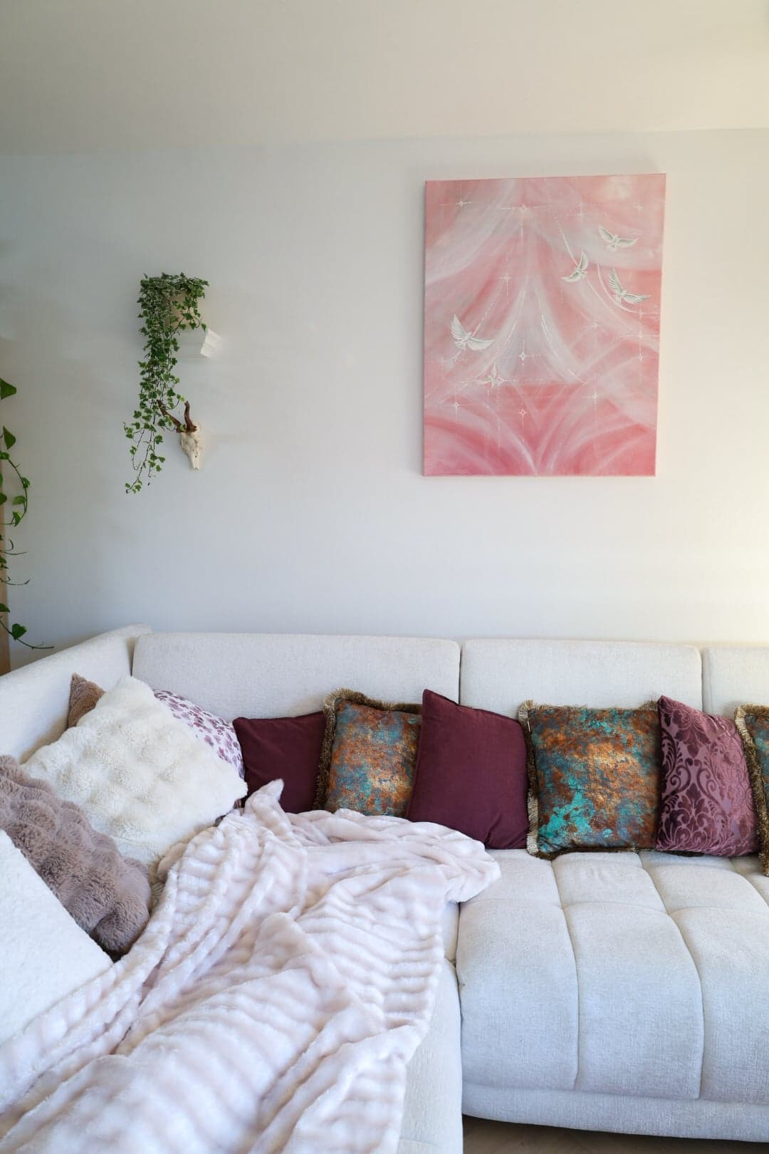 "Birds of Light" above the sofa, between trailing ivy and a dreamcatcher
